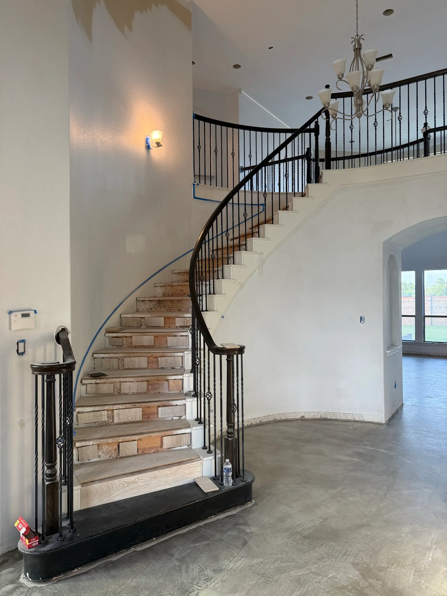 Before: curved staircase with carpet removed and bare concrete subfloor